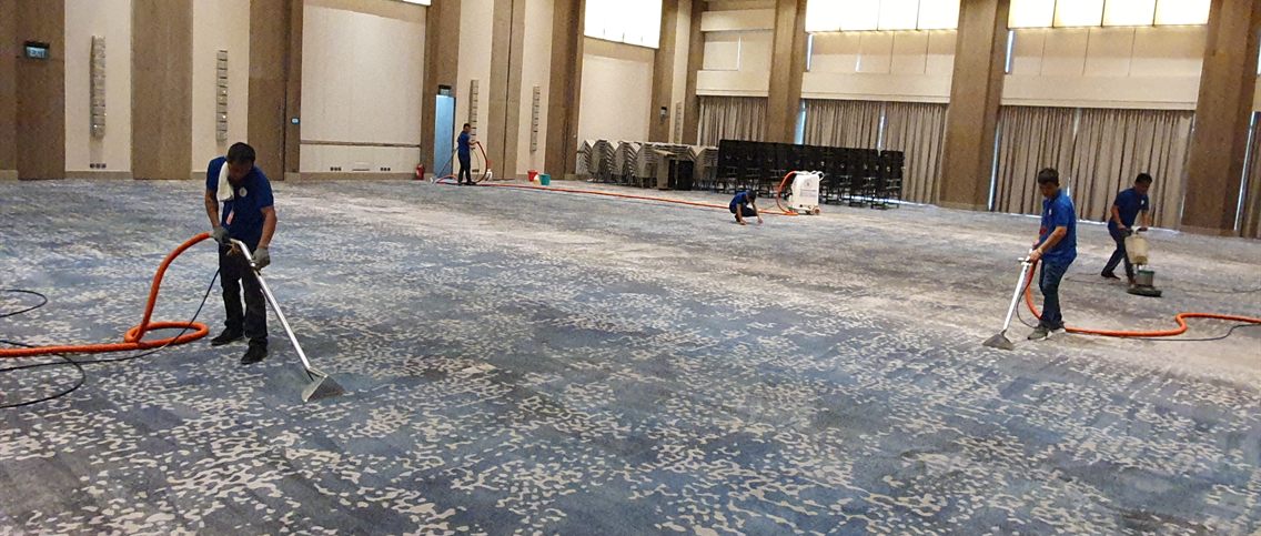 LCCS crew steam-cleaning a hotel ballroom carpet - five technicians with extraction wands, trolley extractor, and orbital scrubber